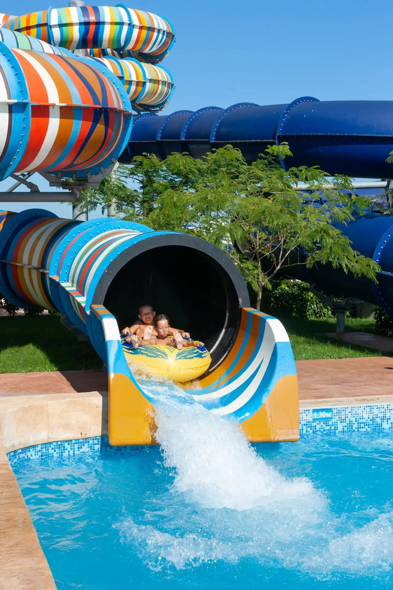 children on a rubber boat in the water park ride down the water slide